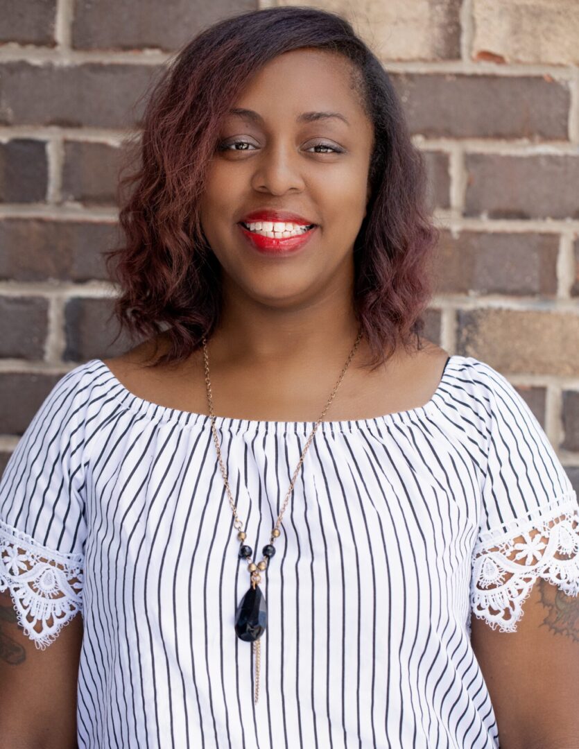 A woman standing in front of a brick wall.