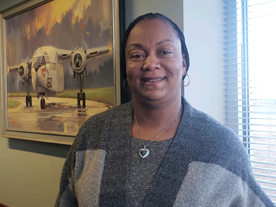 A woman standing in front of an airplane painting.