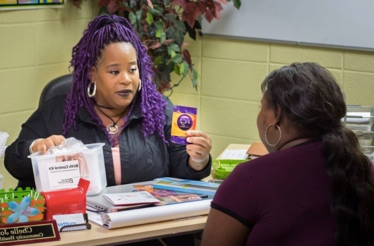 A woman with purple hair holding up a card.