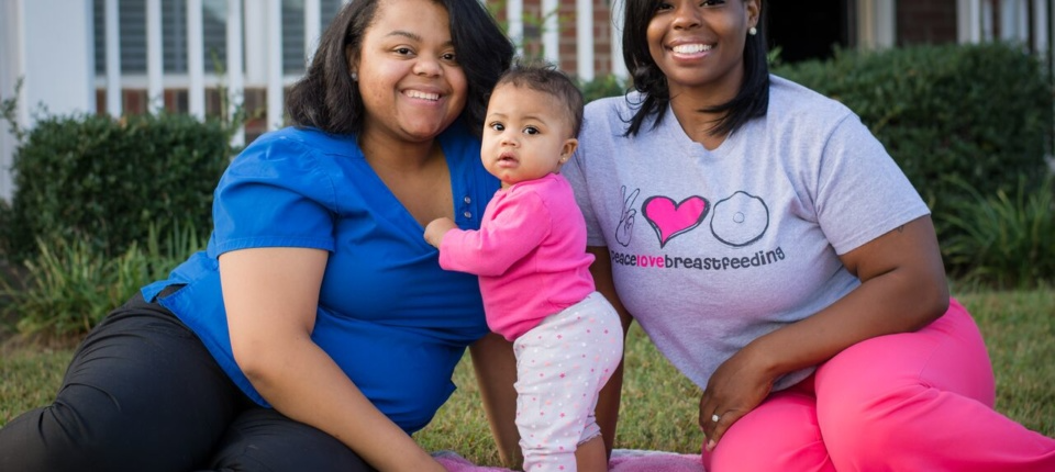 Two women and a baby pose for the camera.