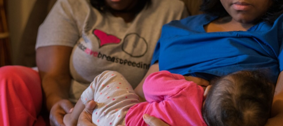 A woman holding two baby girls in her arms.