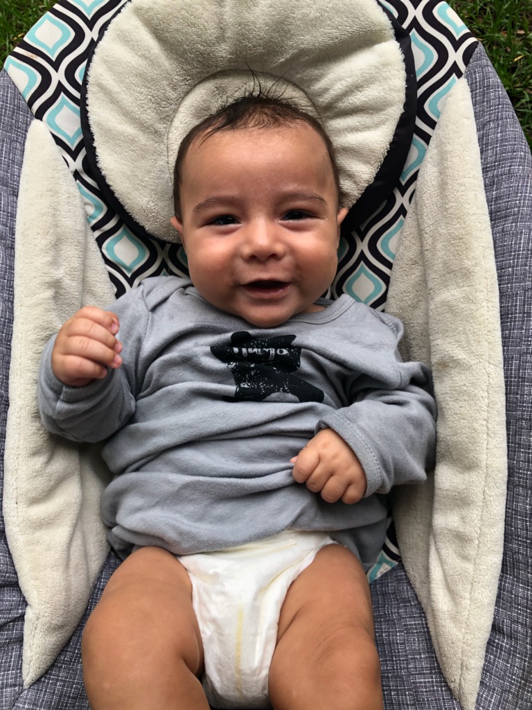 A baby in a stroller with his head resting on the back of it.