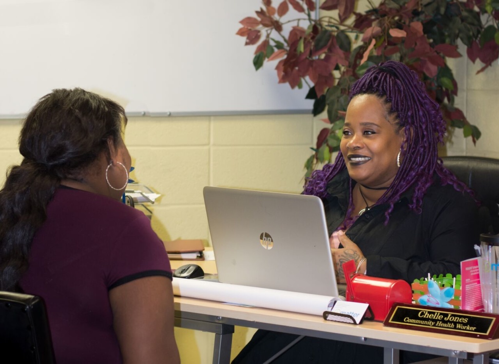 Two women sitting at a table with a laptop.