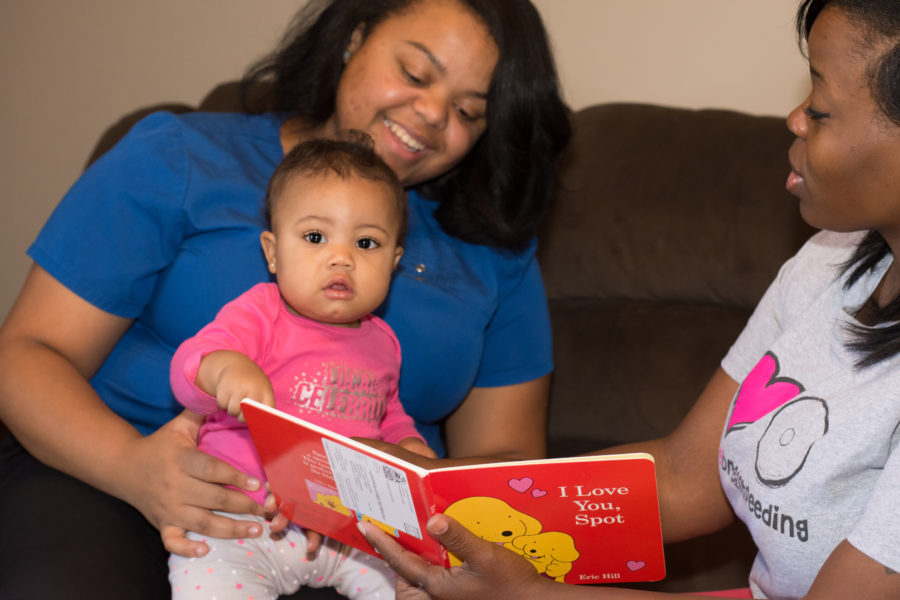 A woman reading to a baby on the couch