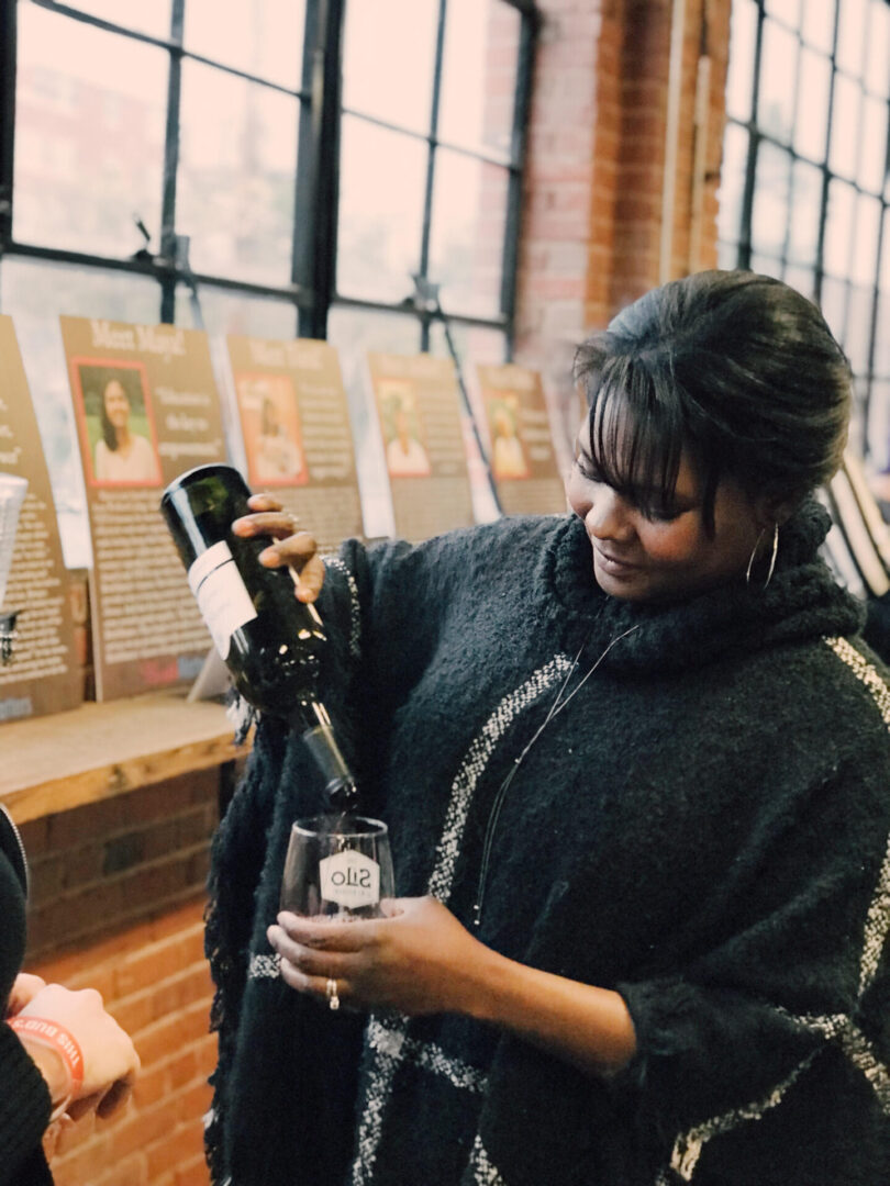 A woman pouring wine into a glass.