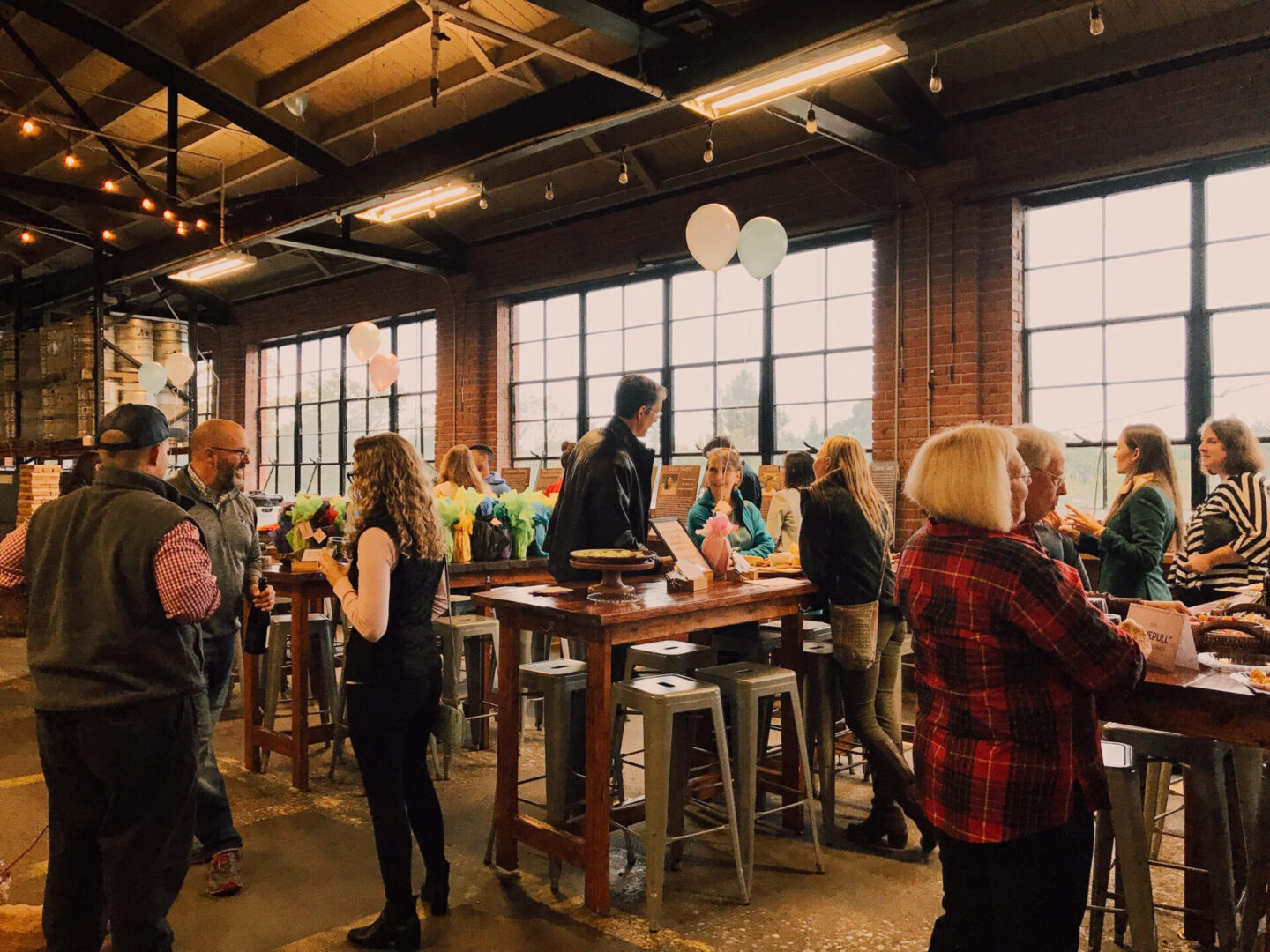 A group of people standing around tables in a room.