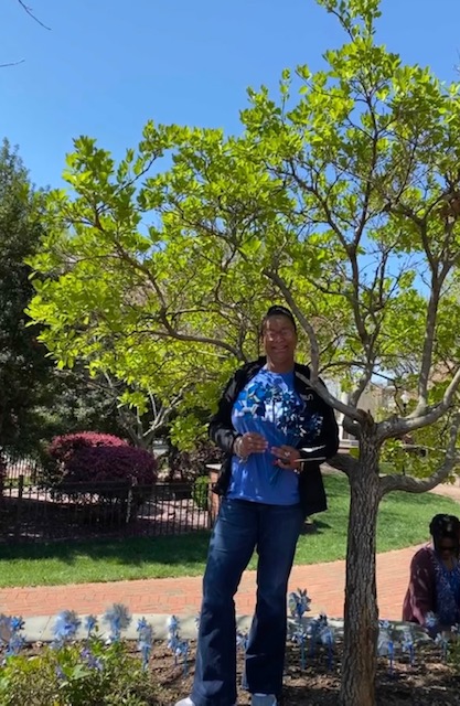 A man standing next to a tree in the park.