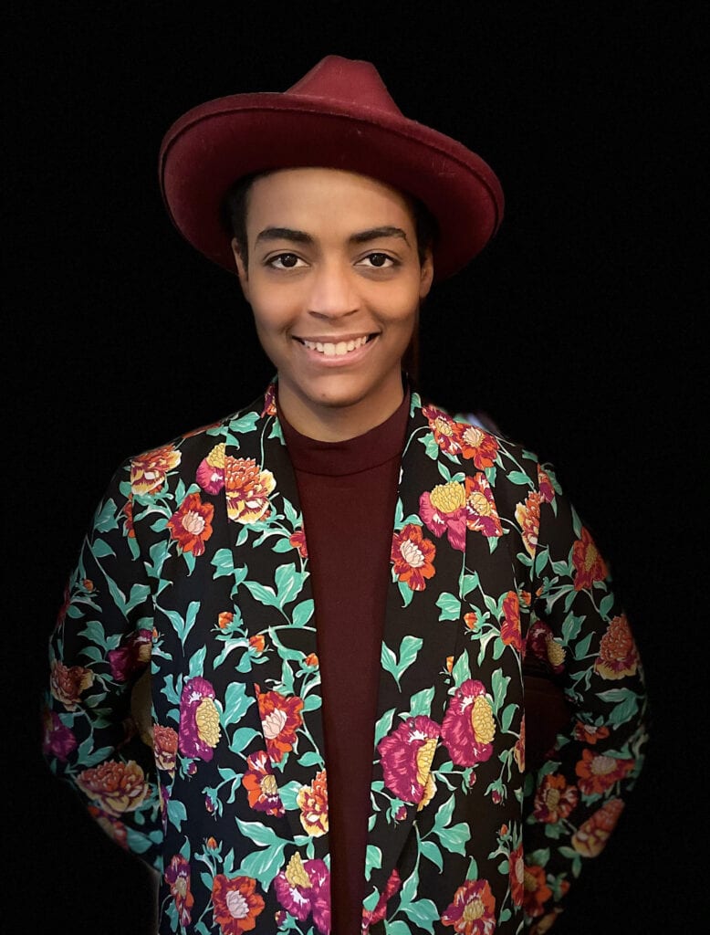 A person wearing a floral jacket and hat.