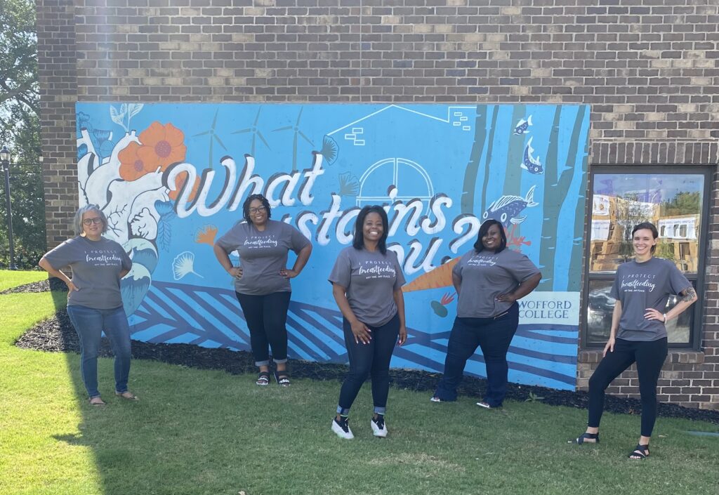 A group of people standing in front of a mural.