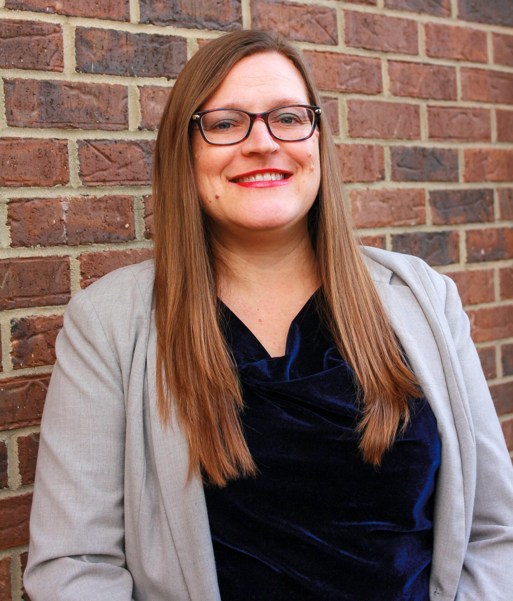 A woman standing in front of a brick wall.