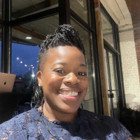 A woman with braids smiles for the camera.