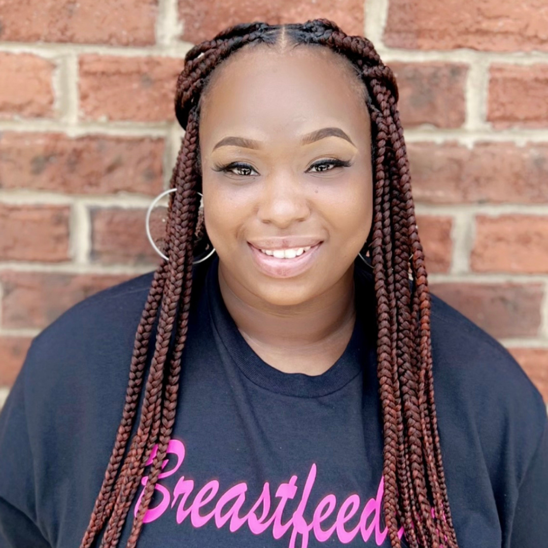 A woman with braids smiles for the camera.