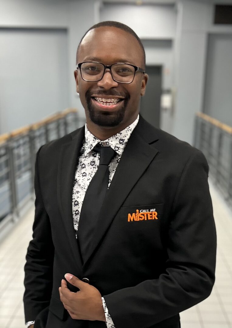 A man in a suit and tie standing next to a wall.