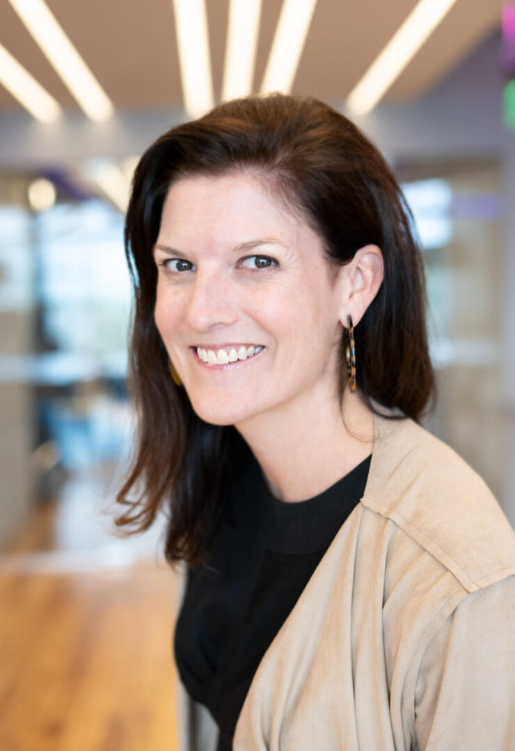 A woman with long hair and black shirt smiling.